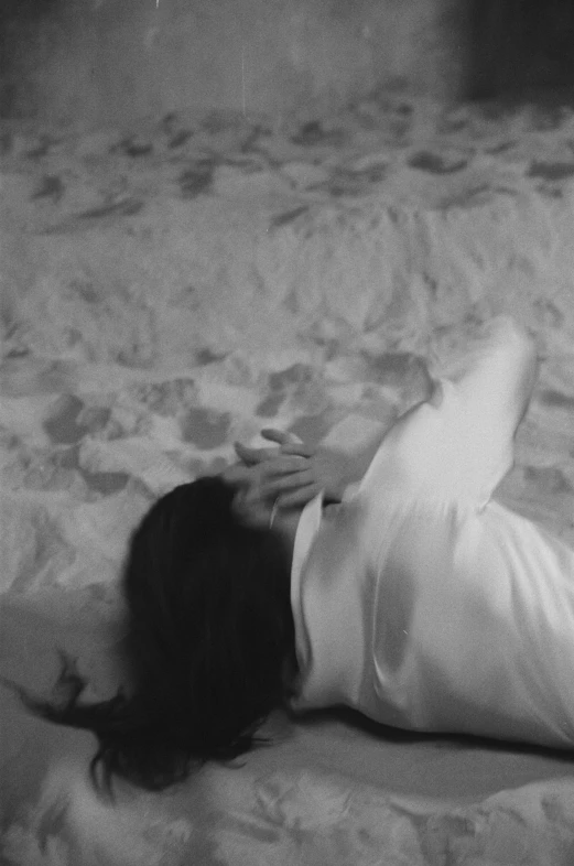 a black and white po of a woman with long hair laying down on a bed