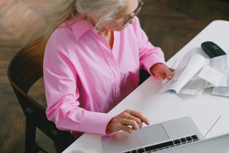 an old lady is typing on her laptop