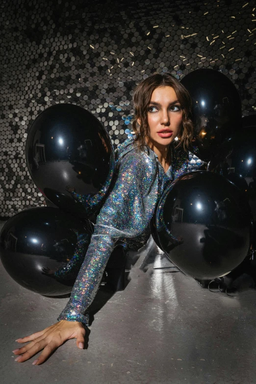 woman with dark makeup holding shiny black balloons