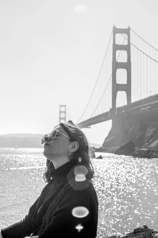 black and white po of a woman outside looking up at the bridge