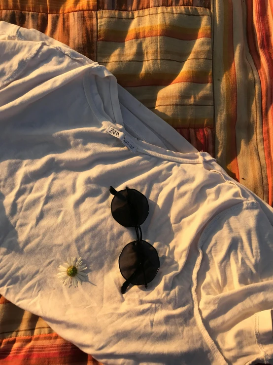 the sun is setting and the sunglasses are on a top of a shirt