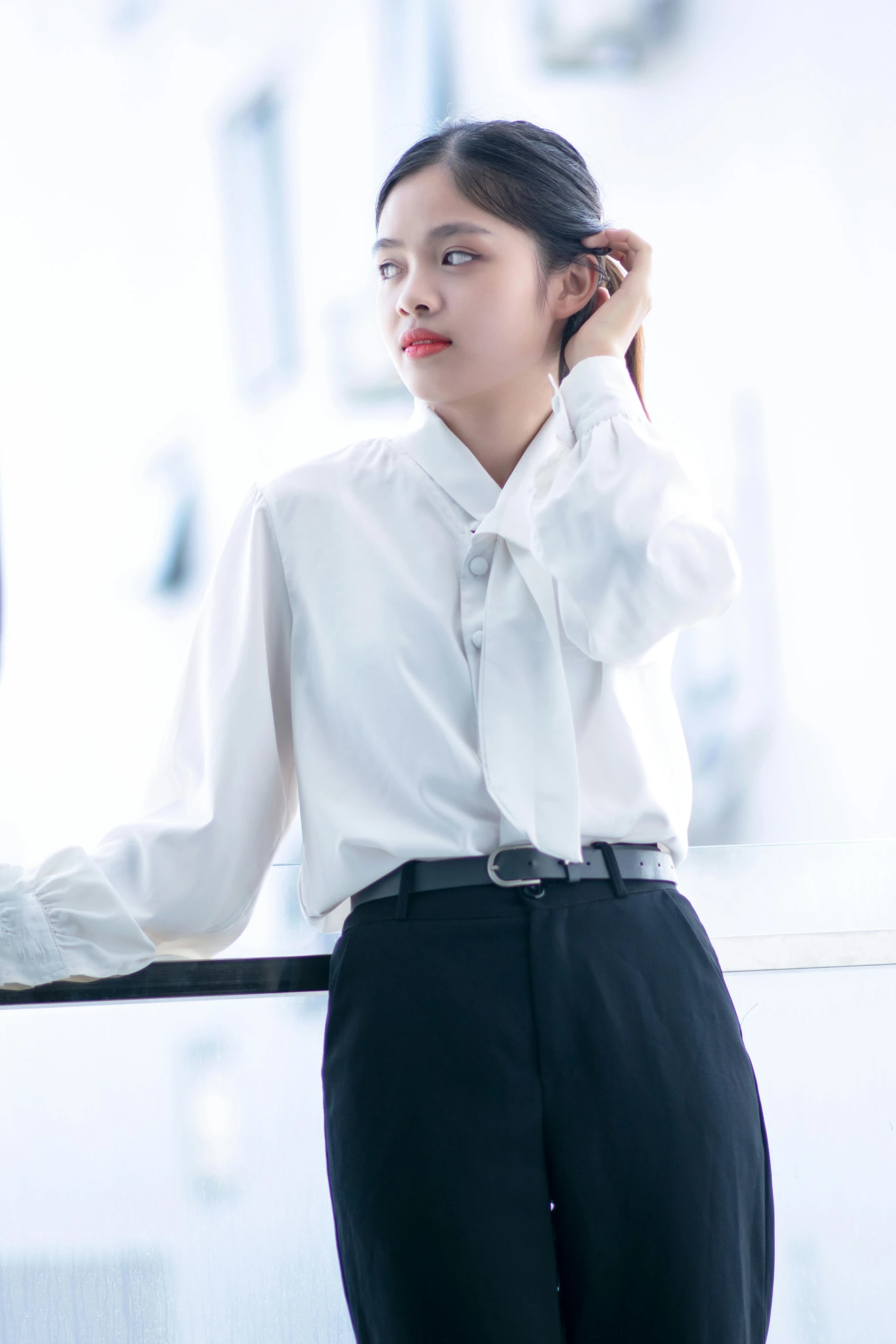 a woman standing on a balcony and wearing a white shirt and black pants