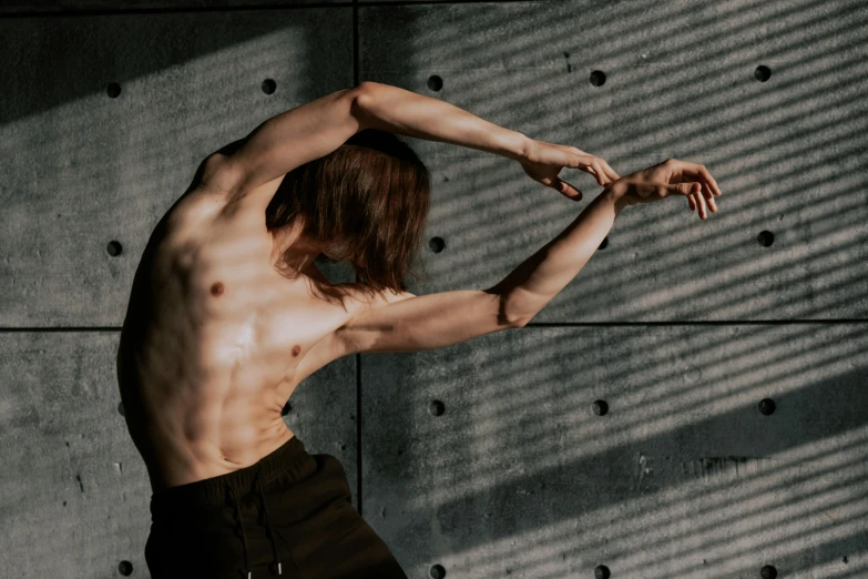 an image of shirtless man standing outside with arms behind his back