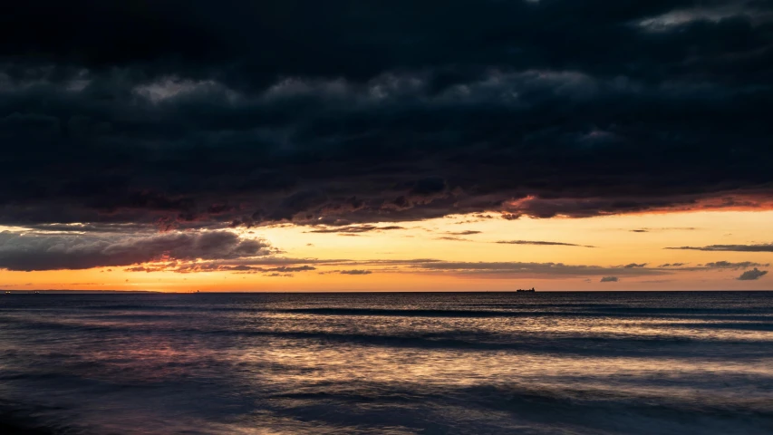 a couple of boats floating in the ocean at sunset