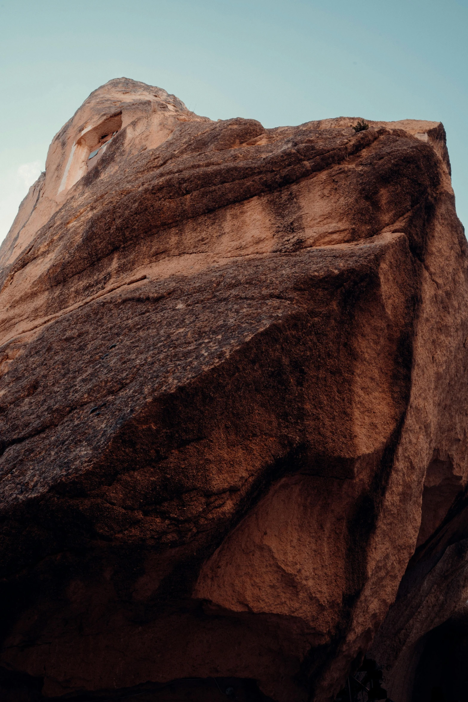 the face of a mountain with an airplane flying low in the sky