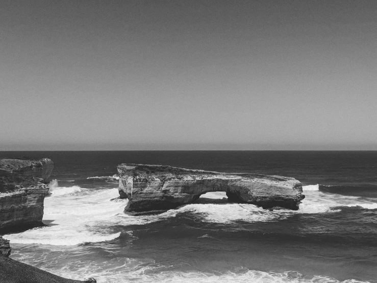 a rocky outcropping on the ocean, with a small pier at the end