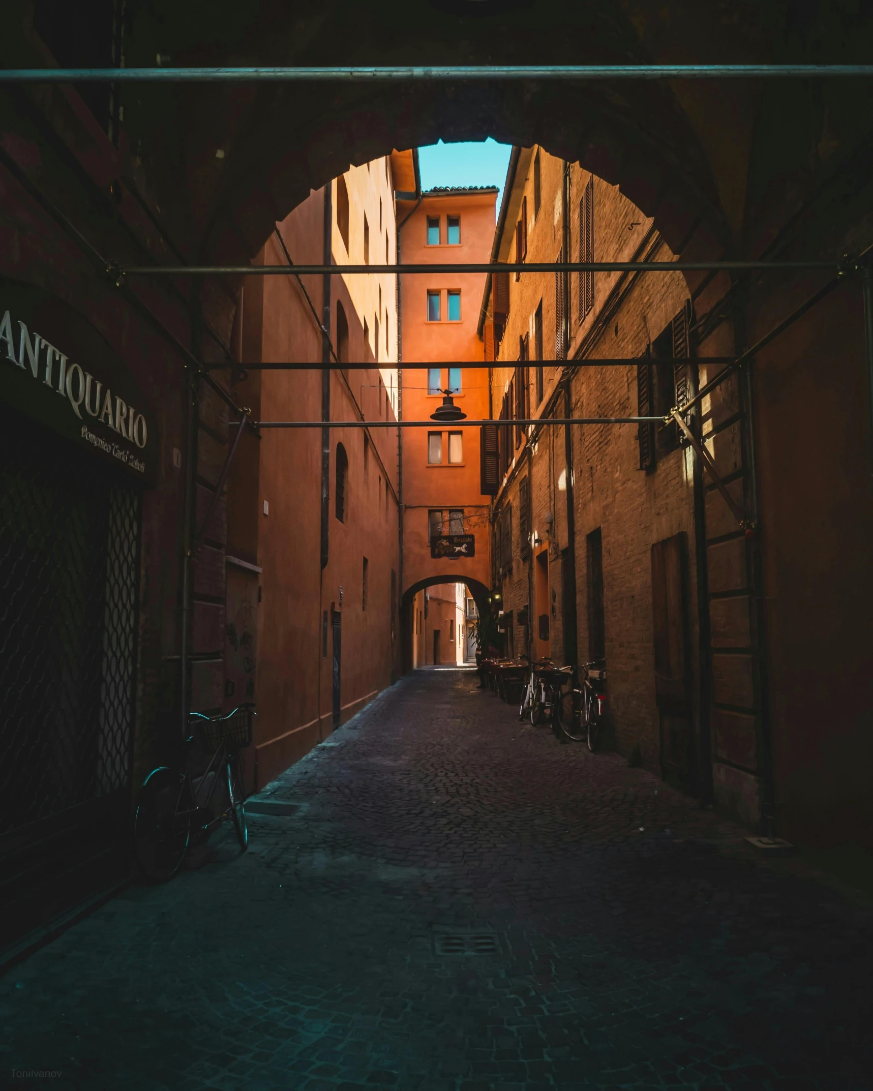 a narrow street with orange buildings and an arched sidewalk