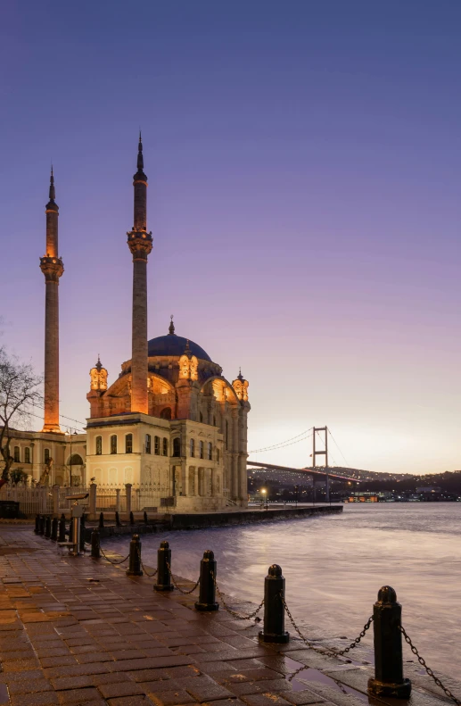 an old mosque sitting beside the water near a bridge