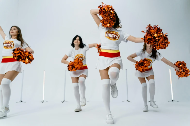 three s wearing cheerleader outfits and holding orange pom - poms