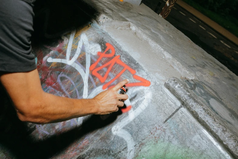 a man who is standing next to graffiti on concrete