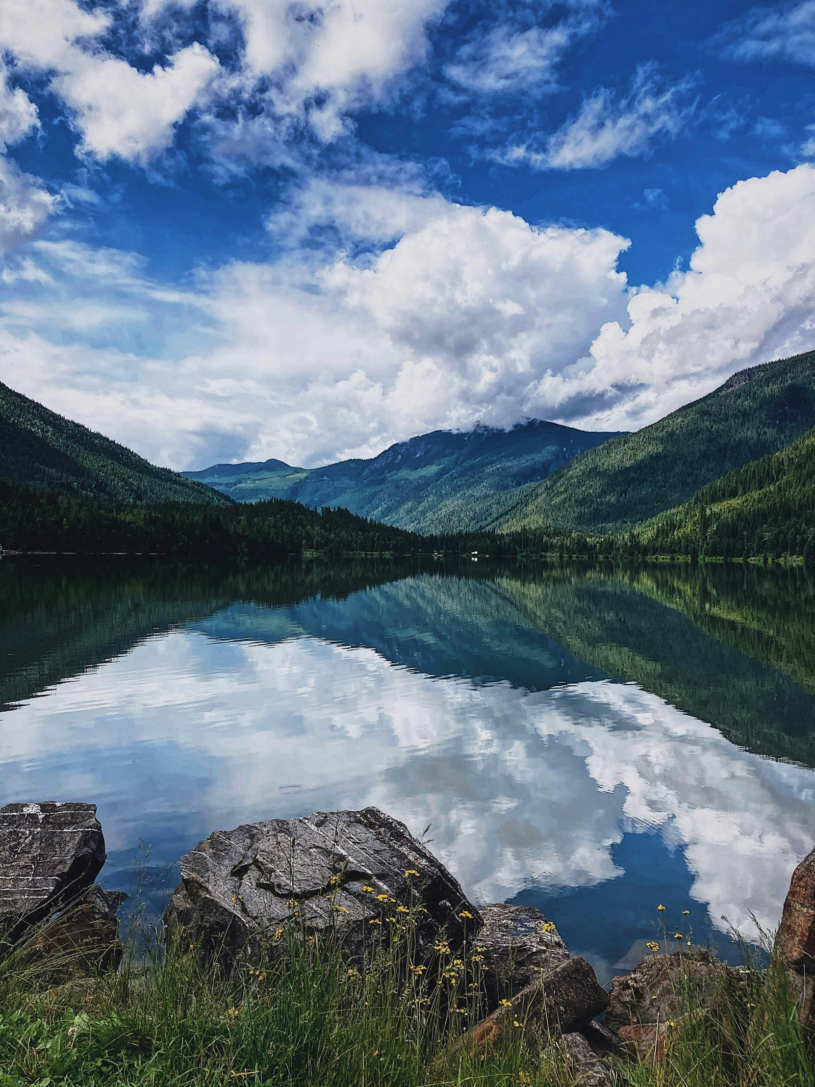 an unspved calm lake sits beneath a blue sky and clouds