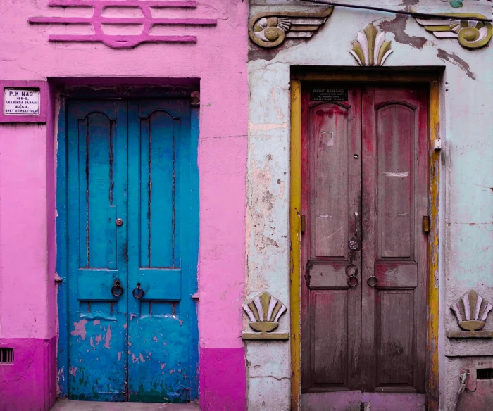 an old building has three blue, pink and brown doors