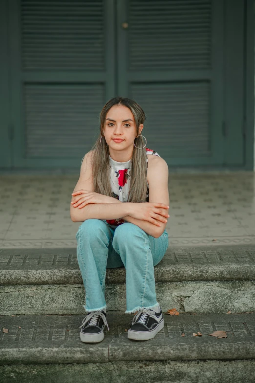 a girl sits on the steps with her arms folded over her body