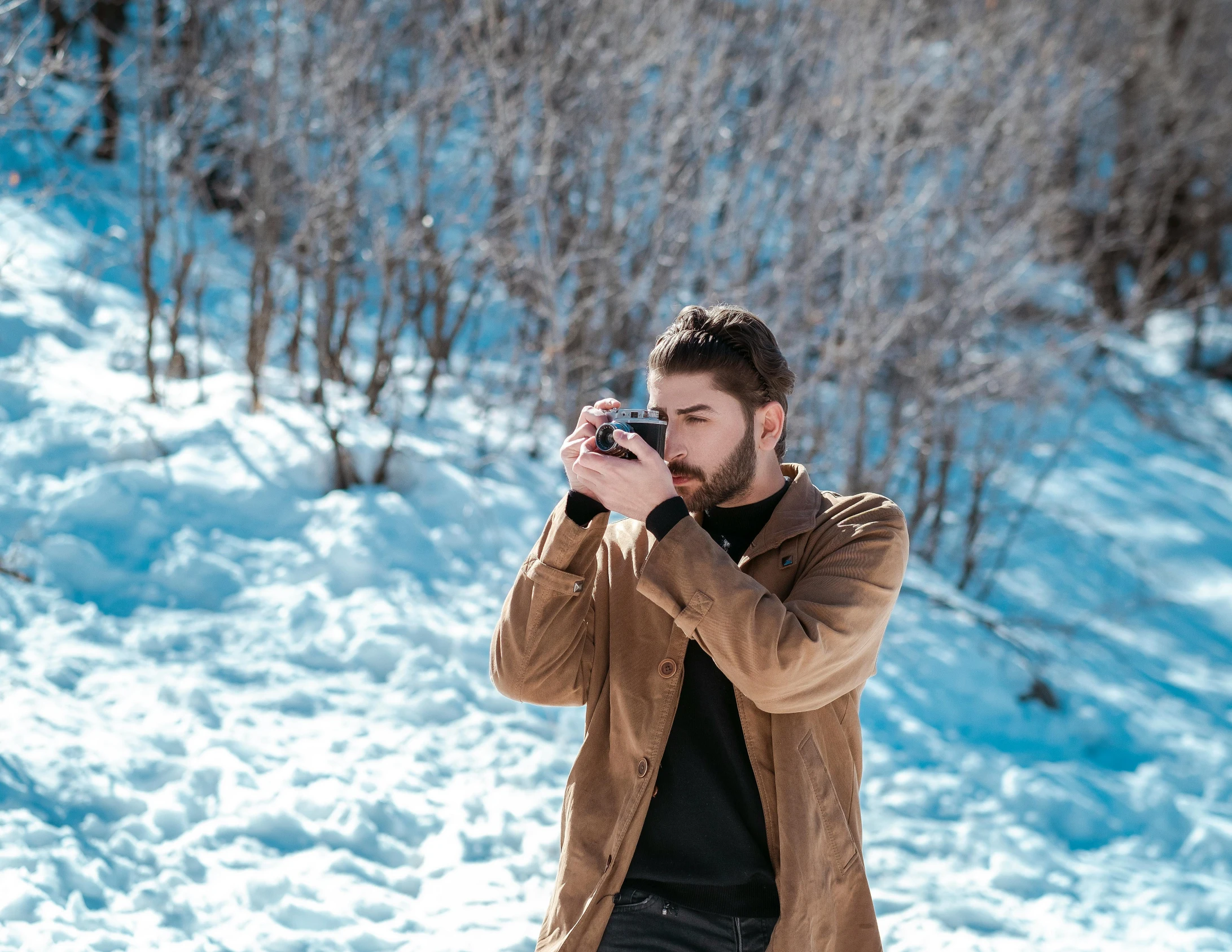 a man holding a camera and standing in the snow