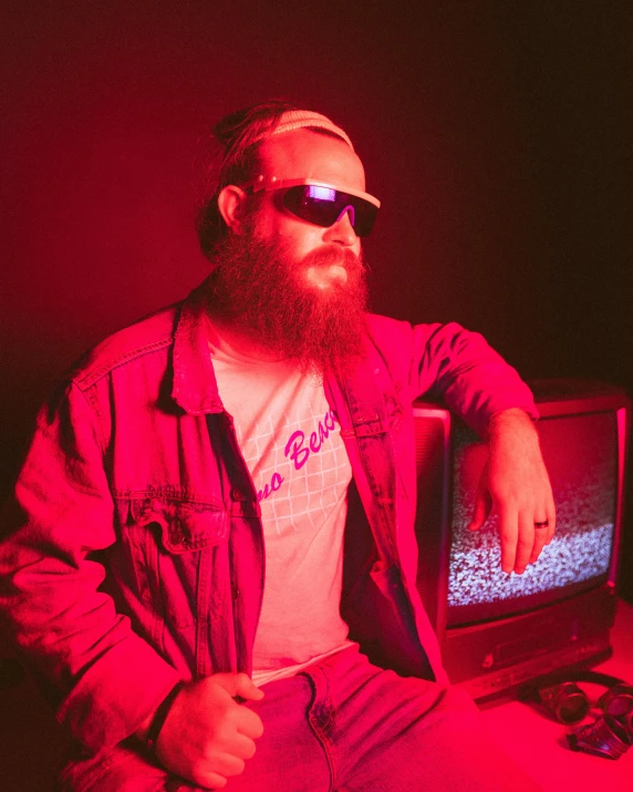 a man with a beard wearing sunglasses sitting in front of a computer