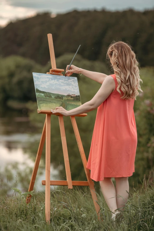 the woman is painting on an easel next to a river