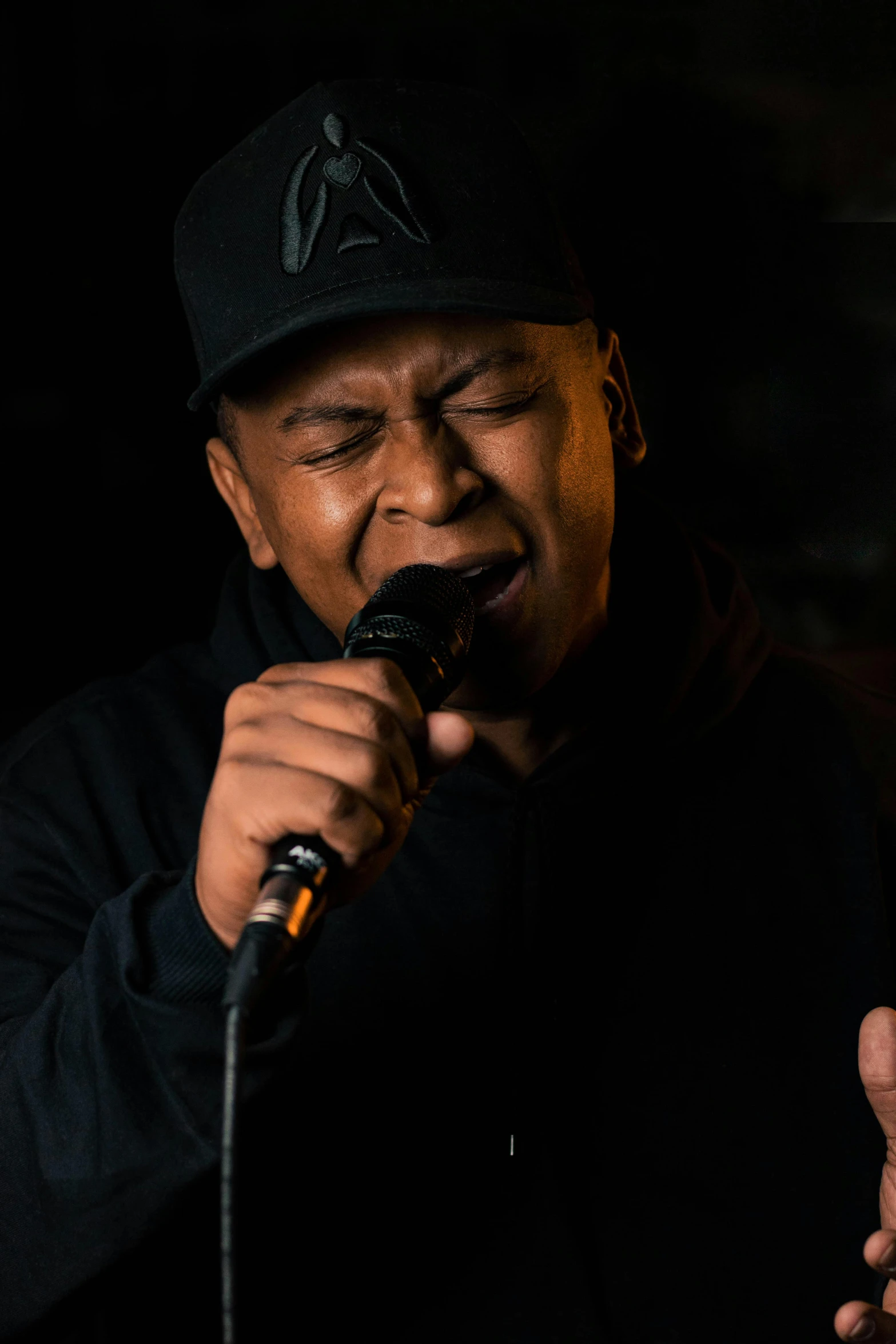 a man singing on a microphone with a black background