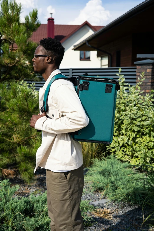 a man carrying a suitcase while standing in front of a building