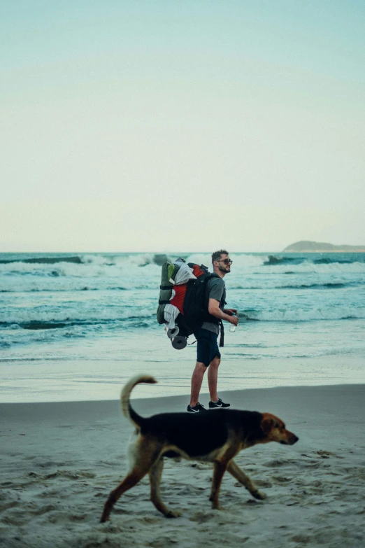 a man with a backpack is walking along the beach