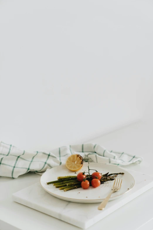 a white plate topped with a fork next to two asparagus