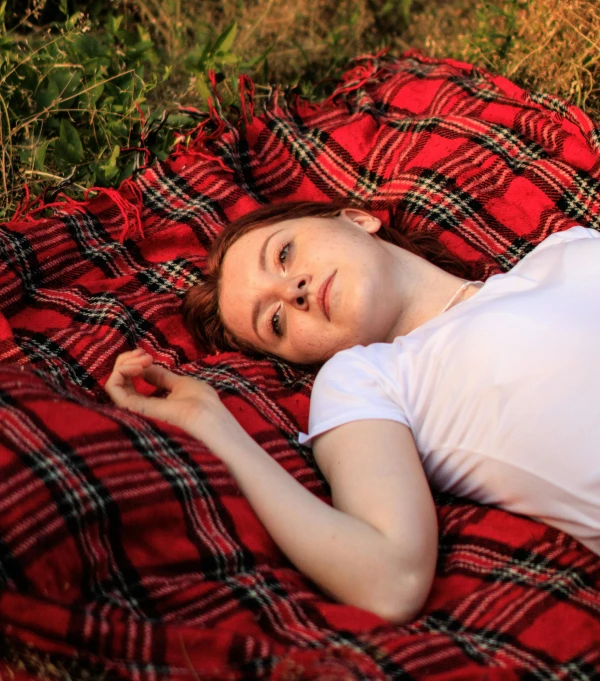 the woman is laying in her bed on the plaid