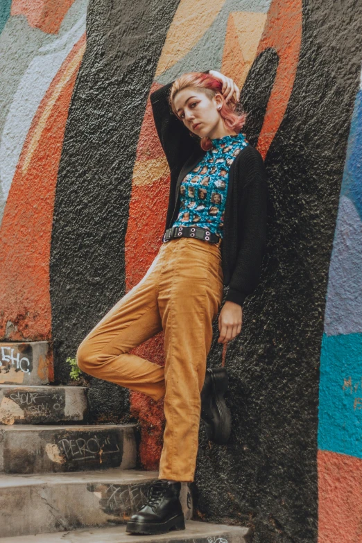 a young woman poses in front of a wall