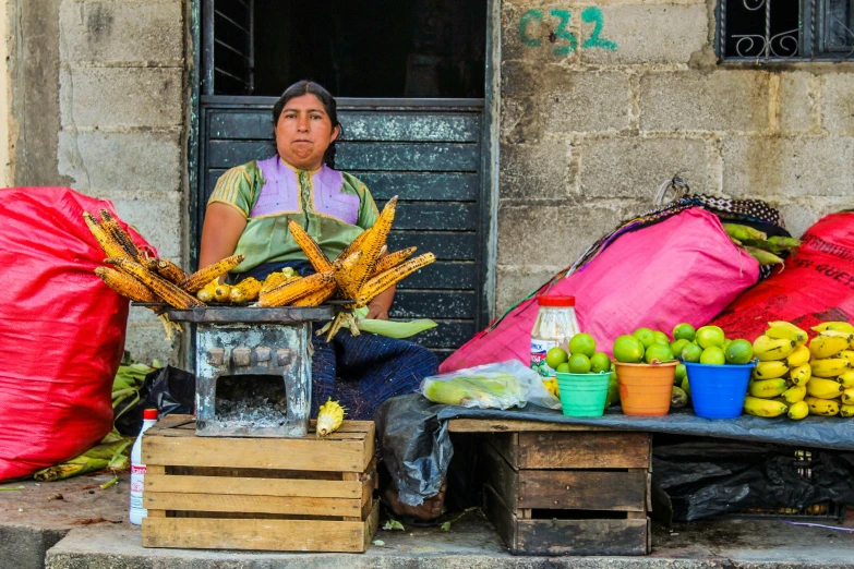 woman selling bananas and other produce outside a building