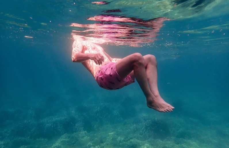 a woman diving under the water with her legs under water