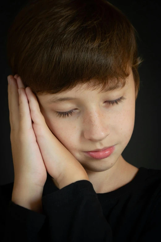 a close up of a young person holding their hand near the face