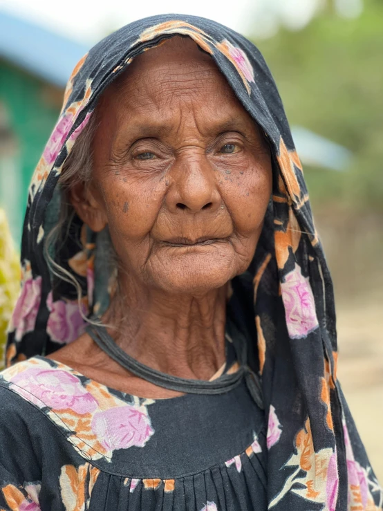 a close up of an old woman wearing a flowered head scarf