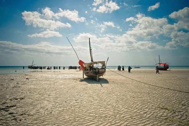 boats are docked on a sandy beach and some people