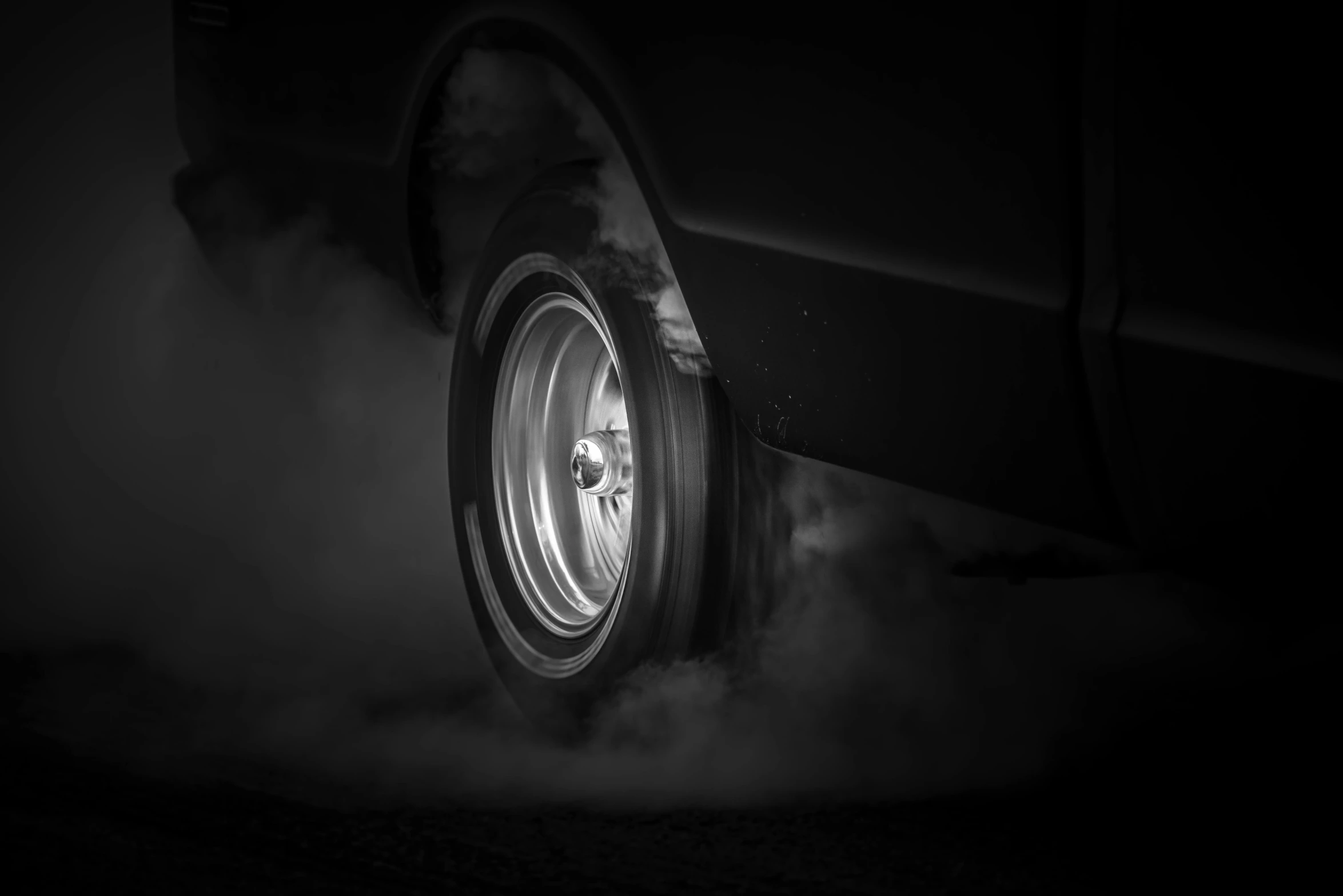 a black and white po of a car wheels with smoke pouring out the wheel