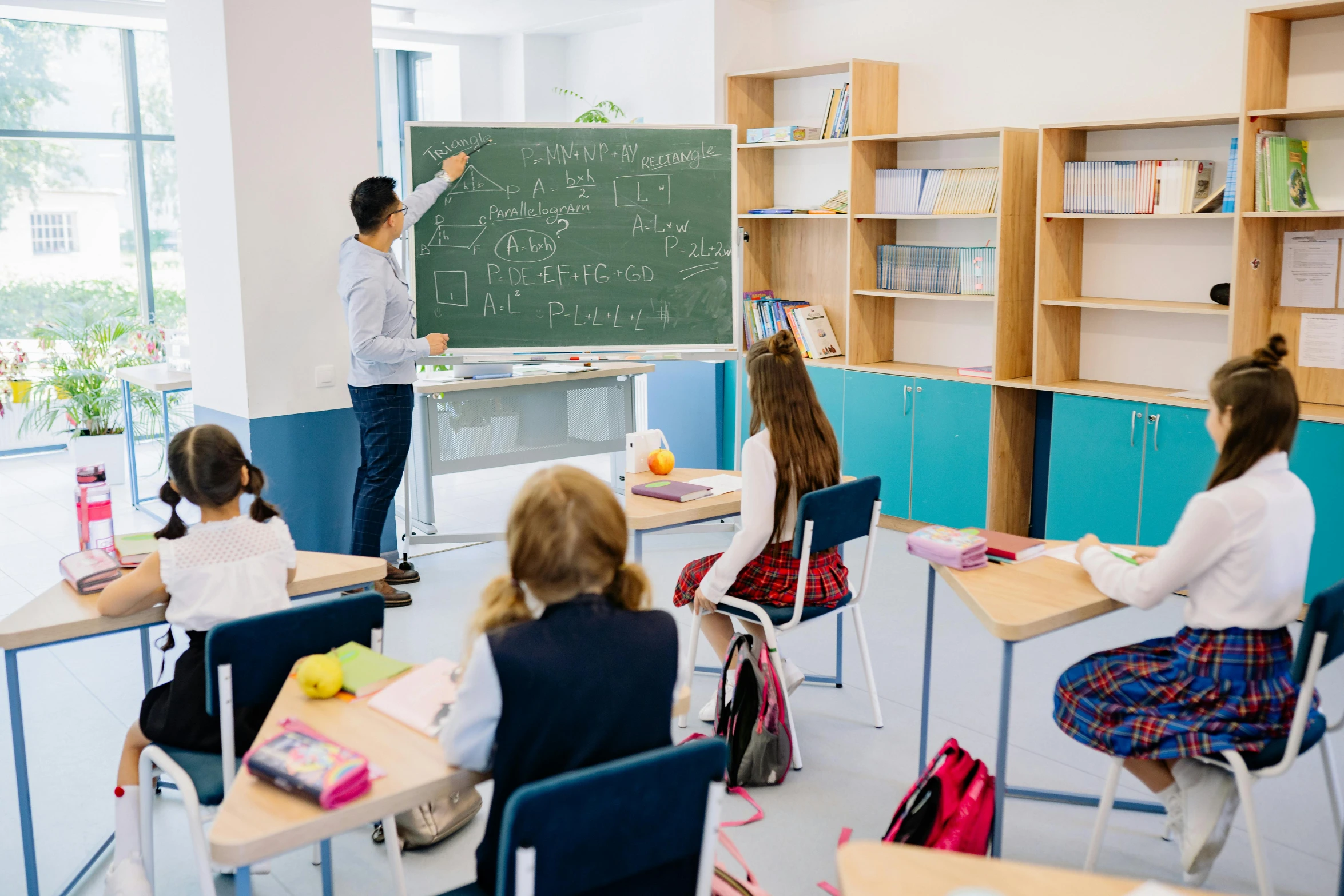 a teacher teaching children on chalkboard in a classroom