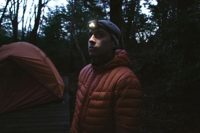 a man standing outside of a tent in the woods