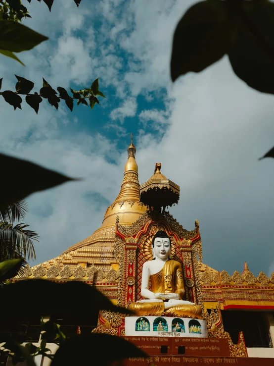 a golden buddha statue sits in front of a blue sky