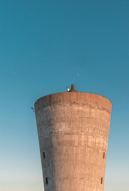 a tall water tower is seen against a blue sky