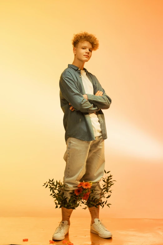 young man posing in front of a yellow wall with his arms crossed