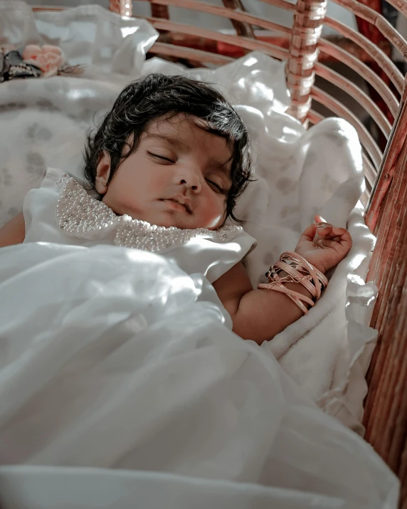 a little baby in a white dress sleeping