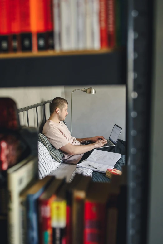 a man on his computer sitting in his bed