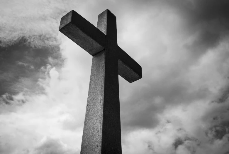 a cross sitting under the dark clouds with no people