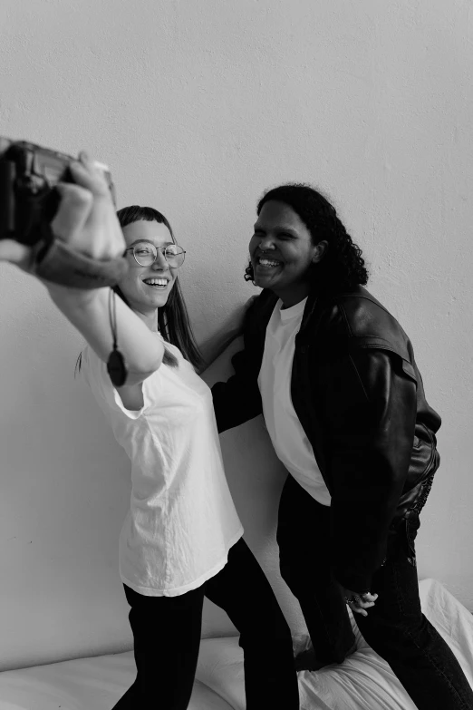 two young ladies standing next to each other while taking pictures