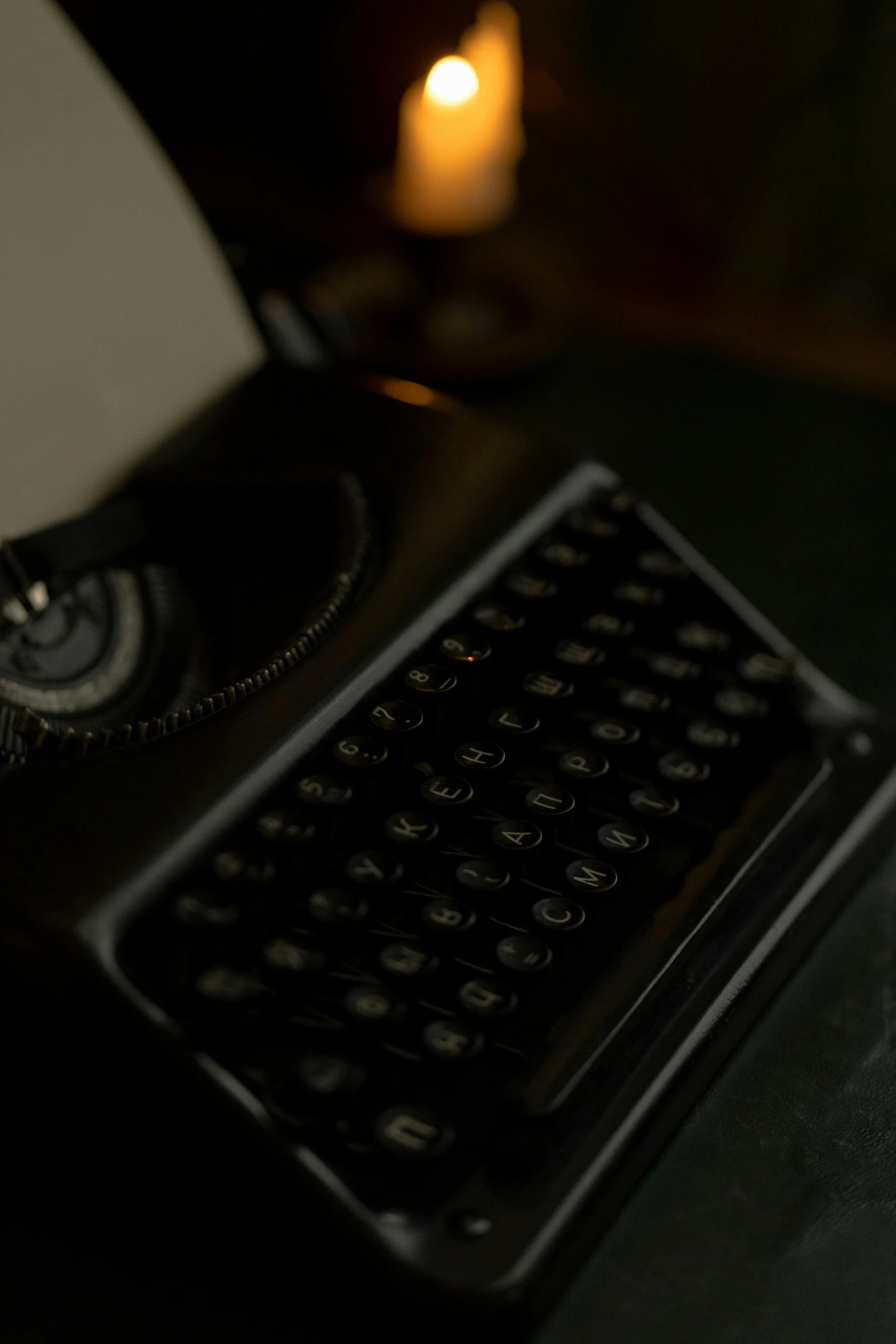 a typewriter on a black desk next to a lit candle