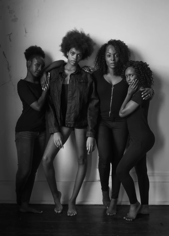 a trio of women, all wearing black clothing, stand together against a wall