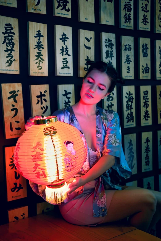 woman holding illuminated lantern with asian writing on background