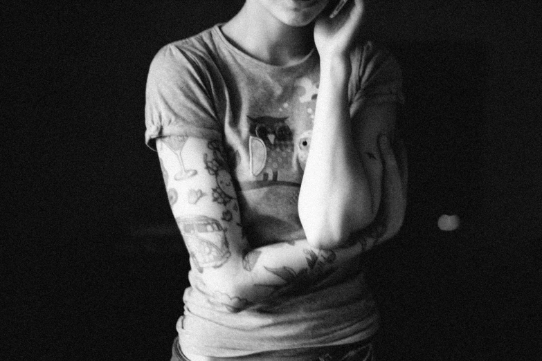 black and white pograph of woman holding hand to her face with tattoo on top