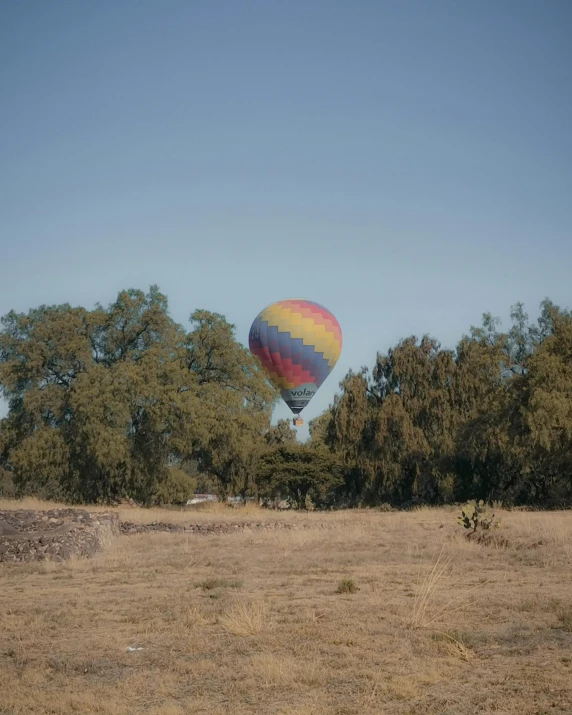 a large balloon is flying over a dry landscape