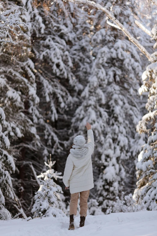 a woman walking down a snow covered street next to trees