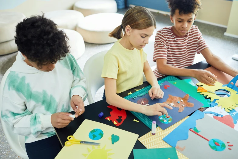 a boy and girl making a cutout craft with colored felt