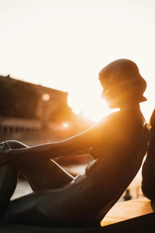 a silhouette of a person sitting against the sunlight