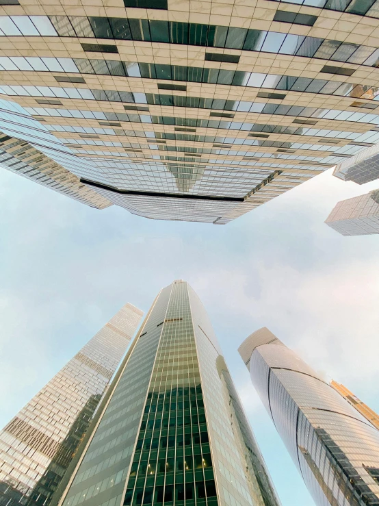 looking up at three skyscrs that appear to be made out of glass